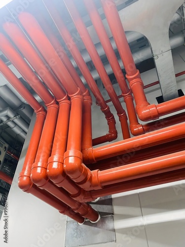 Bright red fire protection pipes installed in a large building, showcasing well-maintained infrastructure and organized pipe layout.