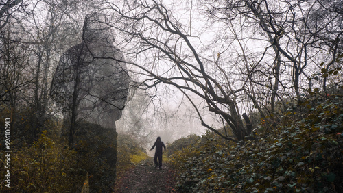 A horror concept. A ghost like hooded figure watching a blurred entity walking down a path. In a spooky foggy winters forest.