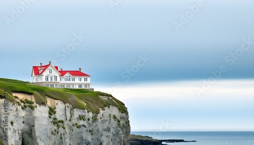 Clifftop white house with red roof gazing over a moody ocean under an overcast sky