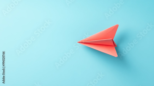 paper plane flying upward on light sky blue background evokes sense of freedom and creativity. Its vibrant color stands out beautifully against serene backdrop photo