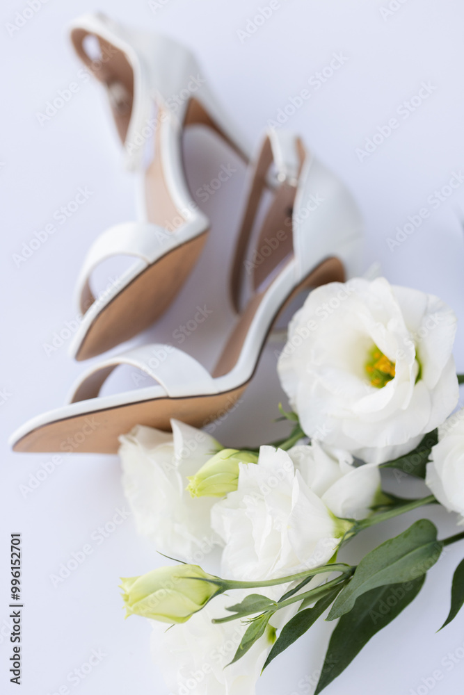 Fototapeta premium White wedding sandals with white flowers. Selective focus.