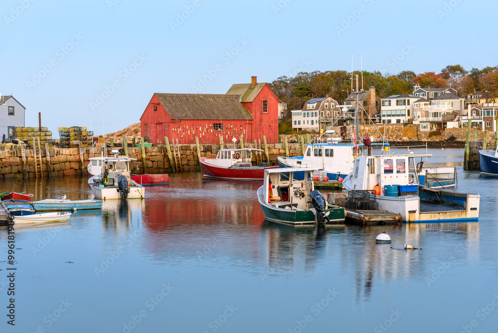 Fishing boats in harbour at twilight in autumn. A red wooden fishing shack on a stone quay is visible in background. Fishing boats in harbour at twilight in autumn. A red wooden fishing shack on a stone quay is visible in background.