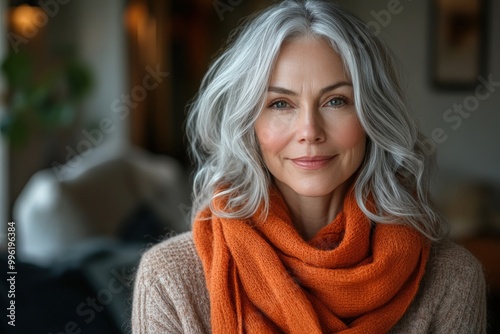 Portrait of a confident, mature woman with silver hair and an orange scarf.