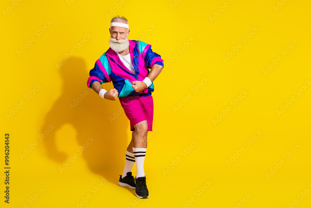 Full length photo of handsome good mood senior guy oldschool sportswear showing biceps emtpy space isolated yellow color background Full length photo of handsome good mood senior guy oldschool sportswear showing biceps emtpy space isolated yellow color background