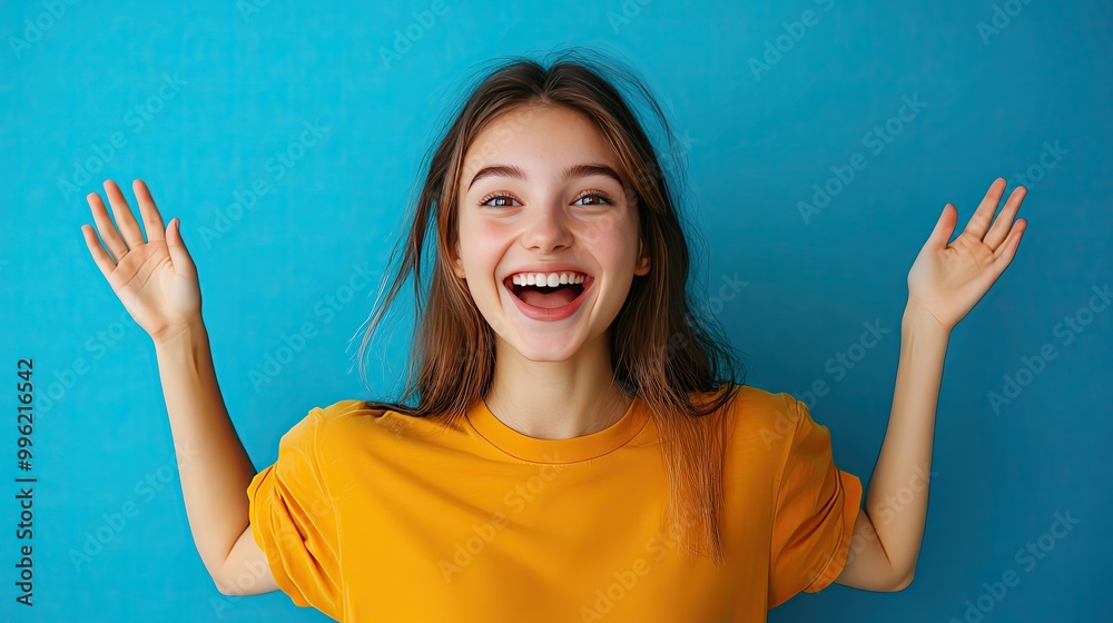 A cheerful young woman with long hair joyfully smiles against a bright blue background, radiating happiness and positivity. A cheerful young woman with long hair joyfully smiles against a bright blue background, radiating happiness and positivity.