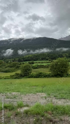 Vertical footage of driving along a mountain winding road in France during rainy weather. View from the passenger’s car side window. Beautiful nature of France Alps
