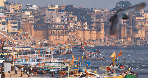 Obraz na płótnie Varanasi, Uttar Pradesh, India. Many Boats are moored to the Ganga riverbank. Tourists boarding for an overnight boats ride on the Ganges River. Cityscape of Varanasi is visible - embankment in the w salonie