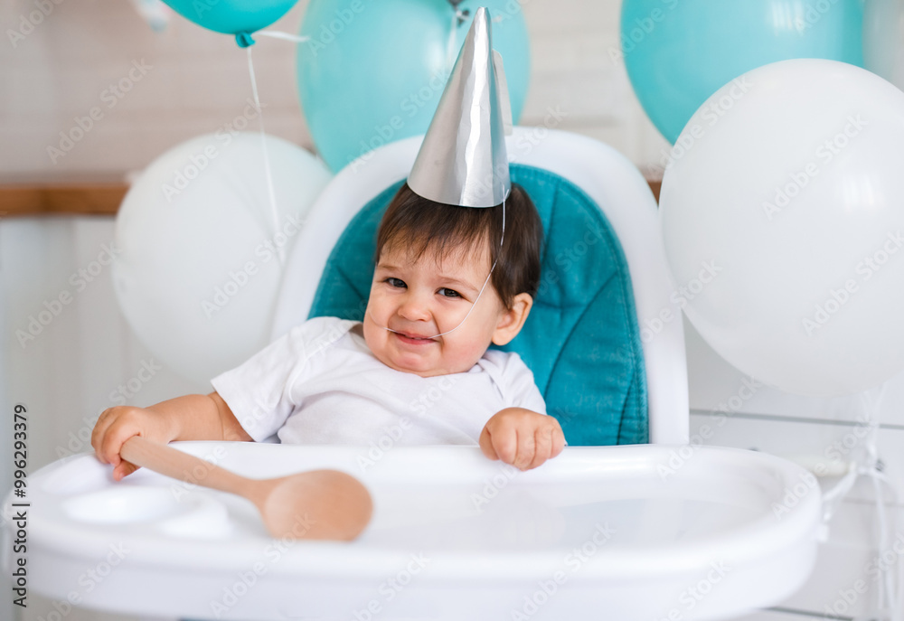 Little baby boy sitting in high chair at home on white kitchen and drinking water from sippy cup Little baby boy sitting in high chair at home on white kitchen and drinking water from sippy cup