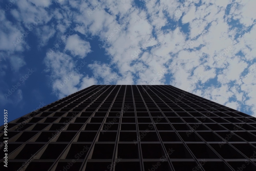 A modern building with the sky and clouds reflected on its facade