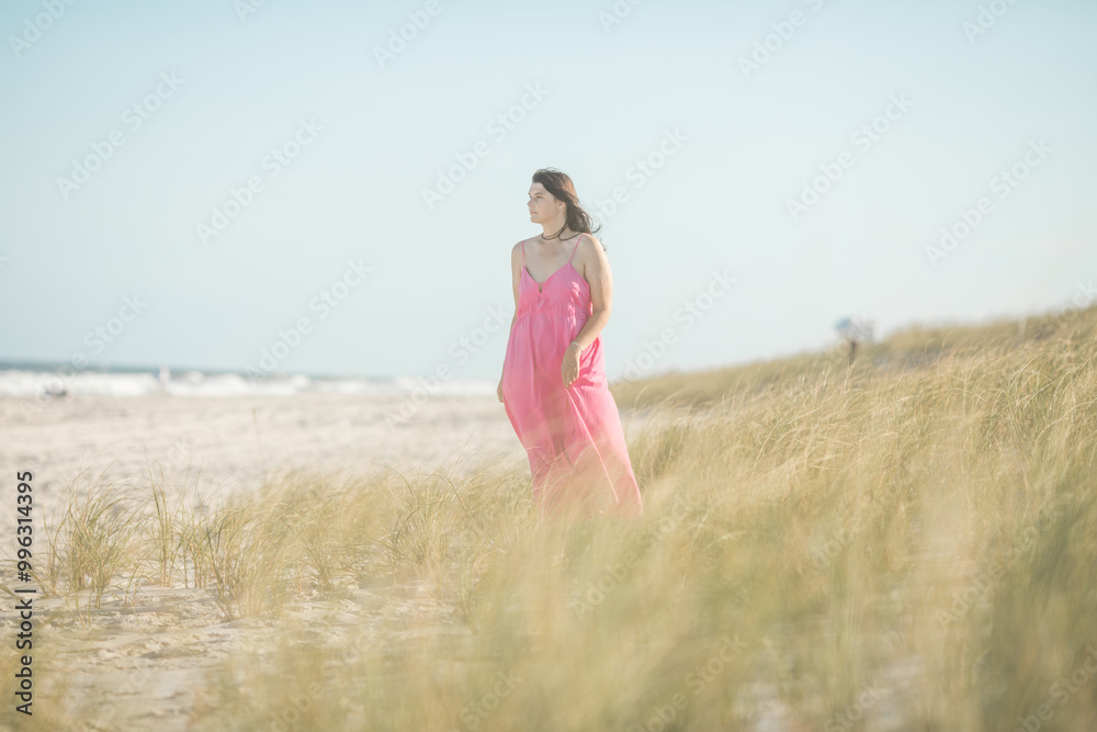 Girl walking on the beach in pink dress front view Girl walking on the beach in pink dress front view