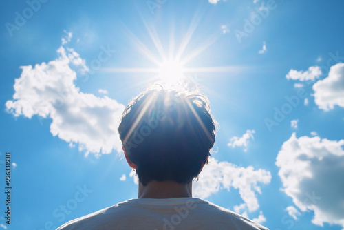 Back view of man looking into sun in blue sky photo
