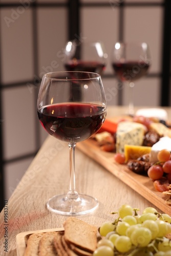 Glasses of red wine and different snacks on wooden table