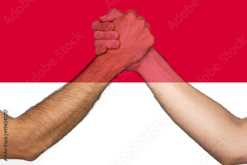 Two hands gathering front of Monaco flag, union of society, togetherness and solidarity concept