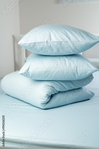 A set of blue bed linen, neatly folded in a pile: a pillow in a pillowcase and a blanket in a duvet cover on a blue sheet. Minimalist bedroom. Cozy home concept. Scandinavian style