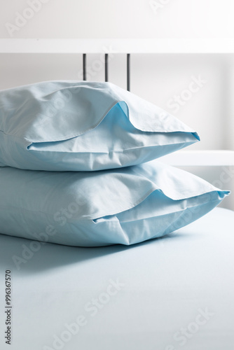 A set of blue bed linen, neatly folded in a pile: two pillows in pillowcases on a blue sheet. Minimalist bedroom. Cozy home concept. Scandinavian style