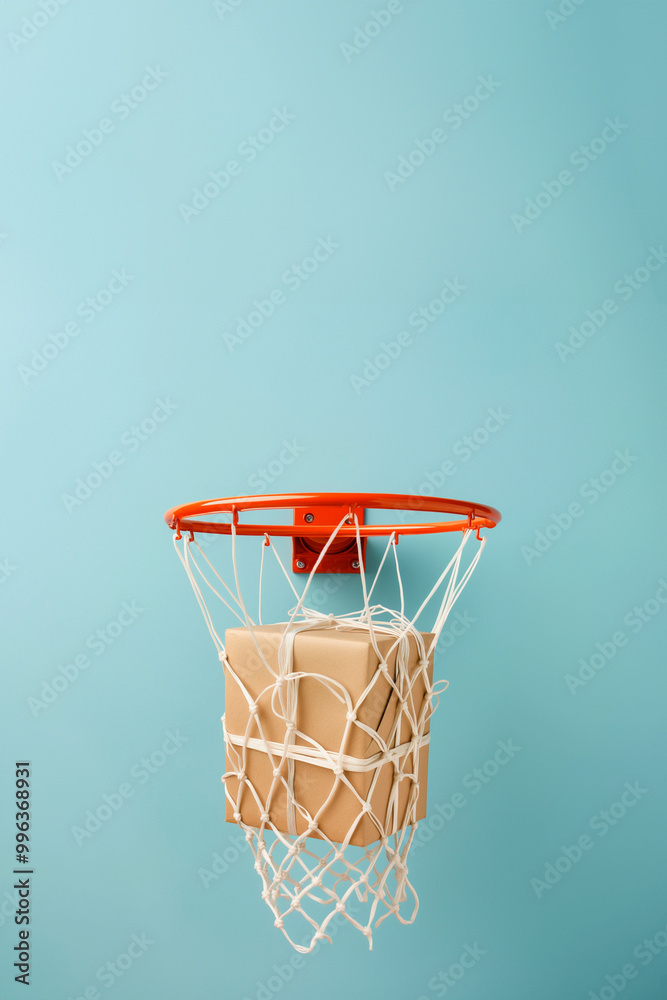 Giftbox is falling in basketball hitting net. A parcel wrapped in craft paper is falling inside the basketball hoop. Success in action, right choice, good work concept. High quality delivery service Giftbox is falling in basketball hitting net. A parcel wrapped in craft paper is falling inside the basketball hoop. Success in action, right choice, good work concept. High quality delivery service
