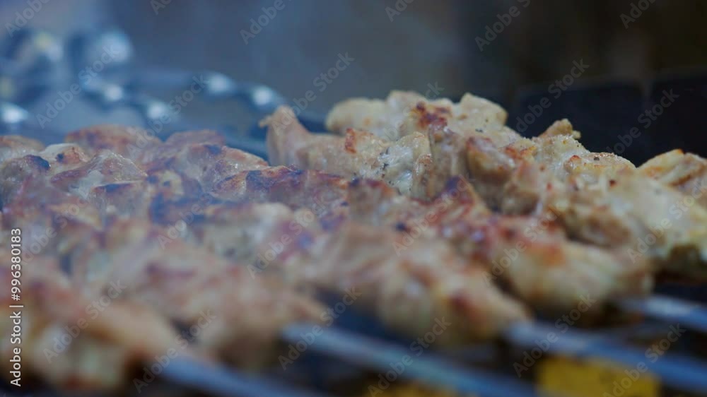 Golden-brown pieces of meat sear on skewers, releasing tantalizing aromas in a lively outdoor gathering. Golden-brown pieces of meat sear on skewers, releasing tantalizing aromas in a lively outdoor gathering.