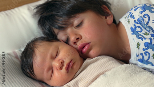 Sweet and tender moment as an older brother kisses his sleeping newborn sibling on the forehead, both lying on a bed, wrapped in warmth and love