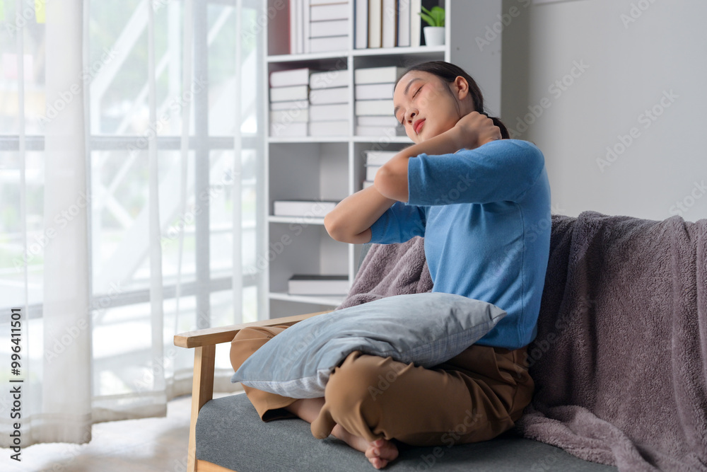 A woman is sitting on a couch with a pillow behind her back A woman is sitting on a couch with a pillow behind her back