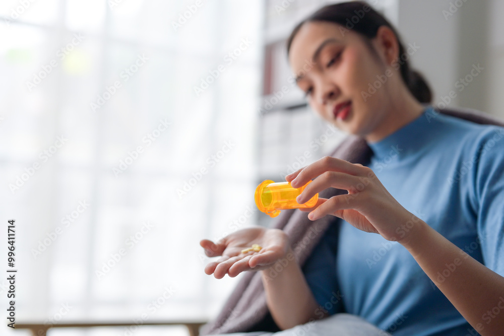 A woman is taking medicine from a yellow bottle A woman is taking medicine from a yellow bottle