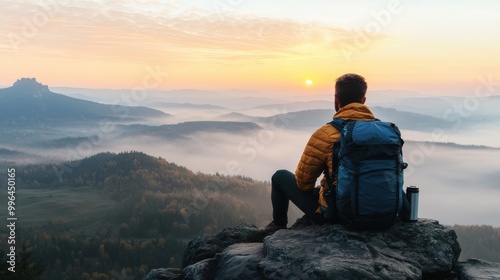 A hiker enjoys a serene sunrise view from a rocky vantage point, surrounded by rolling hills and misty landscapes.
