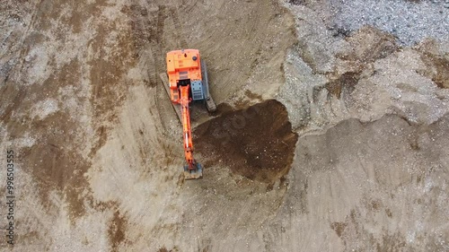 Top down view of excavator loading dump truck on construction site. Excavator is digging hole in ground
