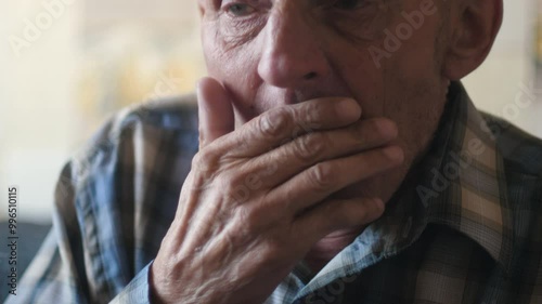 Caucasian pensioner coughs heavily while inside, portrait of old man coughing into hand, colds in old people photo