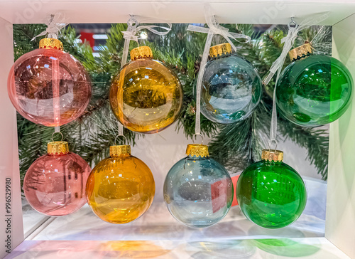 Colorful glass Christmas ornaments hanging from a white frame, against of green pine branches. High quality photo photo