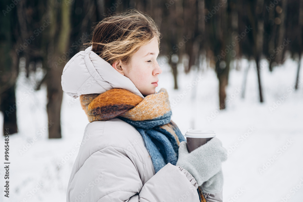 Teenage girl contemplating in snowy forest with coffee Teenage girl contemplating in snowy forest with coffee