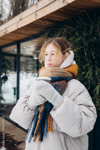 Young girl in warm winter clothing holding a cup of coffee photo