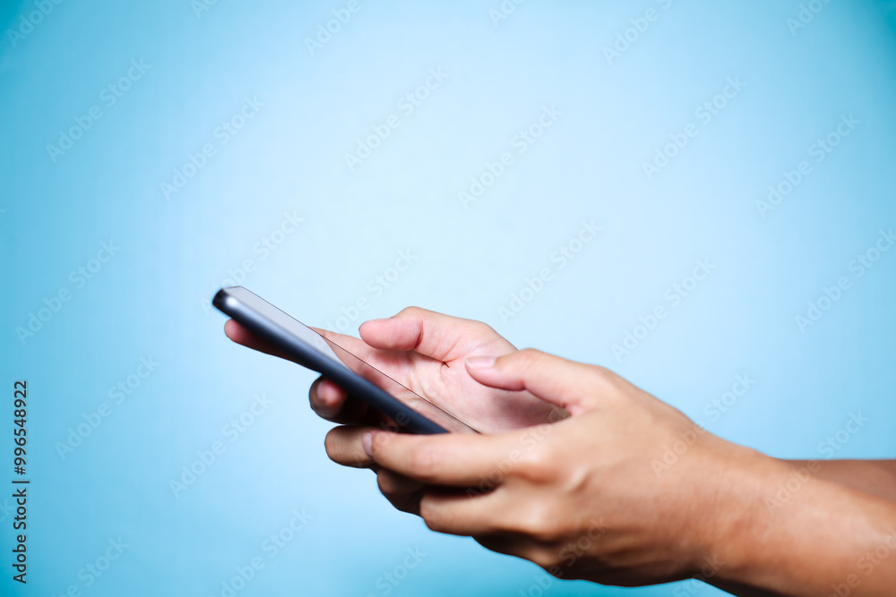 Closeup of hand holding or using smartphone on blue background. Closeup of hand holding or using smartphone on blue background.