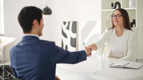 Colleagues shaking hands across a desk in a modern office. The handshake symbolizes a successful business agreement or the end of a positive job interview. Professionalism, success, and partnership