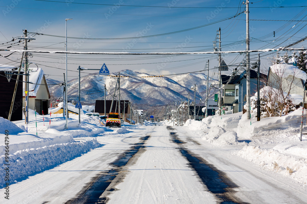 Snow covered roads leading to distant mountains under a blue sky (Niseko, Hokkaido) Snow covered roads leading to distant mountains under a blue sky (Niseko, Hokkaido)