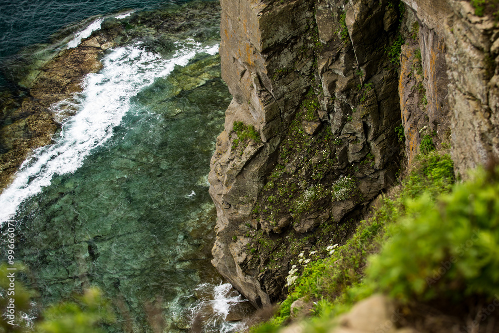 A breathtaking view of a steep cliff that overlooks a vast body of water A breathtaking view of a steep cliff that overlooks a vast body of water