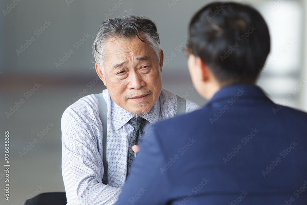 Two Asian businesspeople having a business discussion in the office building. Two Asian businesspeople having a business discussion in the office building.