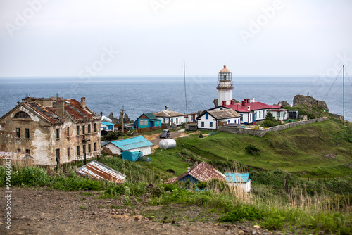 A village with a lighthouse on a hill overlooking the ocean