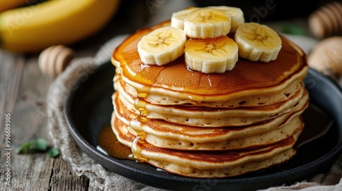 A stack of pancakes topped with banana slices and drizzled with honey