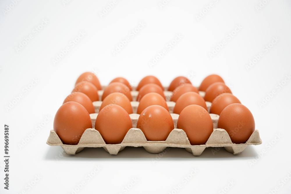 A box of brown eggs on a white background. The eggs are arranged in a row and are all the same size. A box of brown eggs on a white background. The eggs are arranged in a row and are all the same size.