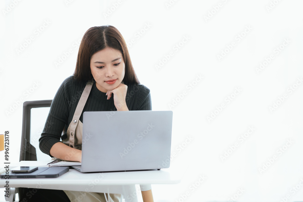 An Asian woman who found success in her e-commerce business, checking orders from a warehouse on her laptop, surrounded by boxes and inventory, fueling the growth of her small startup. An Asian woman who found success in her e-commerce business, checking orders from a warehouse on her laptop, surrounded by boxes and inventory, fueling the growth of her small startup.