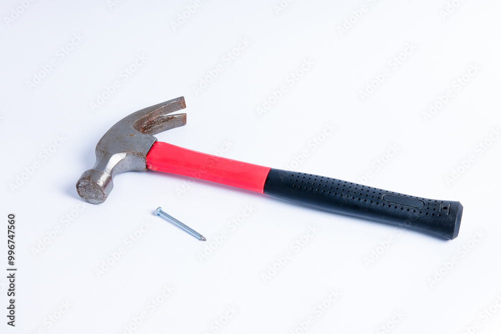 Close up a nail and medium sized hammer that has two functions as a nail pick and nail hammer, with a handle covered in black and red rubber isolated on a white background. Little bit rusty Close up a nail and medium sized hammer that has two functions as a nail pick and nail hammer, with a handle covered in black and red rubber isolated on a white background. Little bit rusty