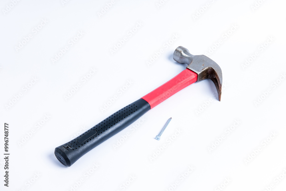 Close up a nail and medium sized hammer that has two functions as a nail pick and nail hammer, with a handle covered in black and red rubber isolated on a white background. Little bit rusty