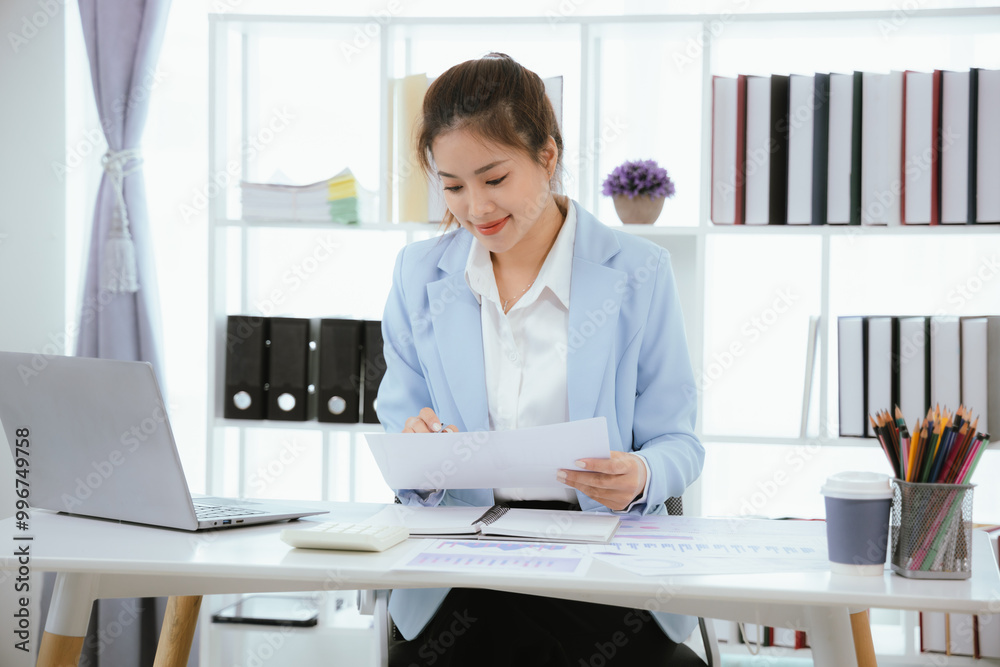 Confident and charming Asian businesswoman using laptop and smartphone. She is full of professionalism and achievement in data analysis, effective communication and organizational management in modern