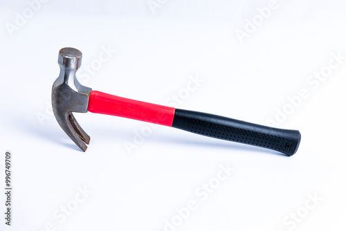 Close up medium sized hammer that has two functions as a nail pick and nail hammer, with a handle covered in black and red rubber isolated on a white background. Little bit rusty photo