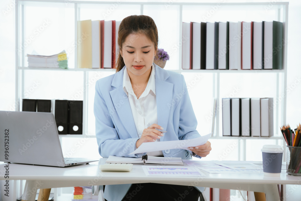 Confident Asian businesswoman in modern office smiling while working on laptop, analyzing reports, planning marketing strategies and leading with energy and positivity. Confident Asian businesswoman in modern office smiling while working on laptop, analyzing reports, planning marketing strategies and leading with energy and positivity.