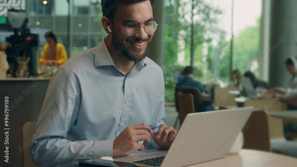 Smiling client tourist male guy Indian Arabian man businessman business worker in earphones chatting video call laptop conference meeting online friendly communicate in cafe computer distant studying