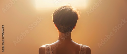 Minimalist portrait, back view of a woman with short hair, warm light, soft focus, neutral background
