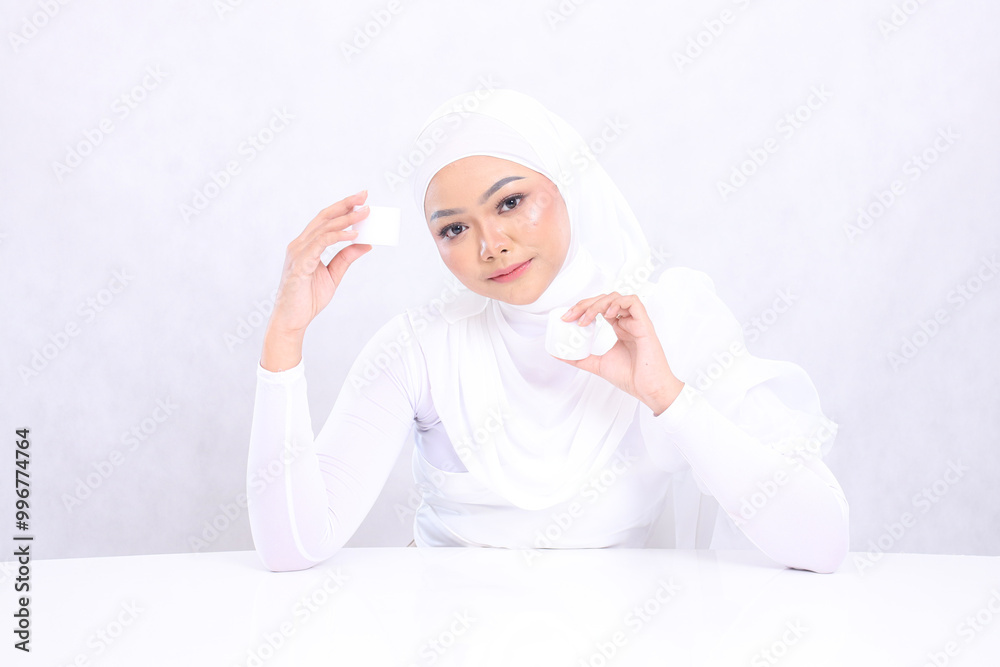 Charm Beautiful young hijab female relax forward both hands holding cosmetic cream satisfied in her skin care routine on white background. Perfect skin, Natural makeup Charm Beautiful young hijab female relax forward both hands holding cosmetic cream satisfied in her skin care routine on white background. Perfect skin, Natural makeup
