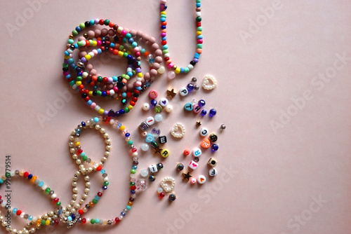 Obraz na płótnie Colorful DIY necklaces, friendship bracelets and various plastic beads on pastel pink background. Flat lay. w salonie