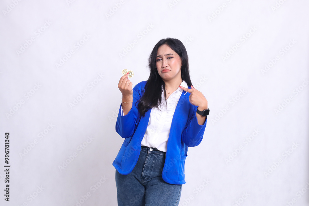 beautiful adult office girl wearing blue formal suit standing crying to camera holding bitcoin while pointing at it isolated white background. for transaction, investment, business content beautiful adult office girl wearing blue formal suit standing crying to camera holding bitcoin while pointing at it isolated white background. for transaction, investment, business content
