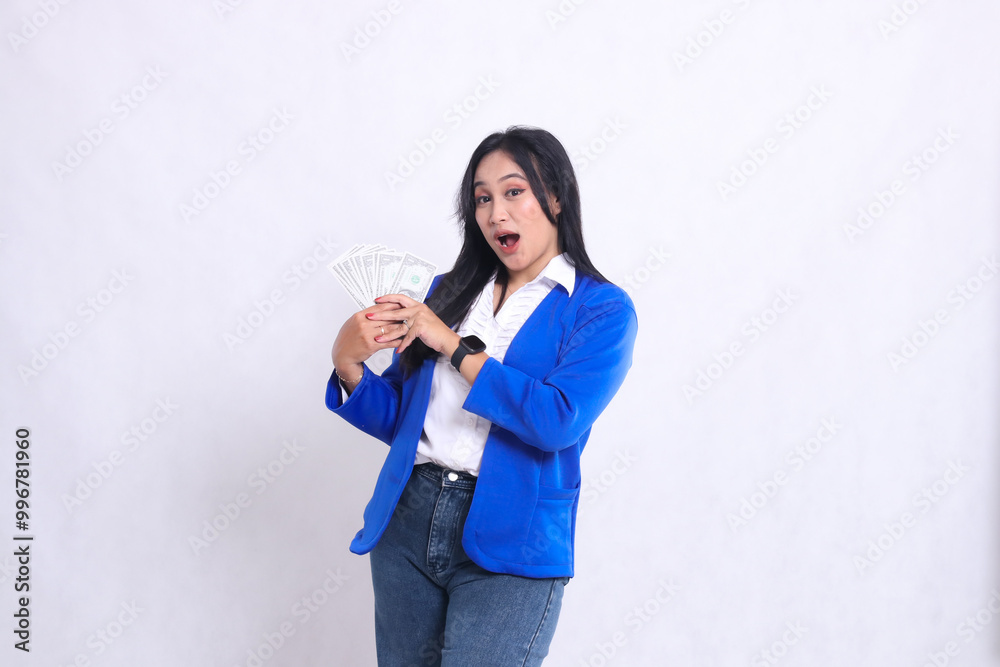 beautiful adult office woman wearing blue formal suit standing surprised to camera both hands holding dollar bill to right isolated white background. for transaction, finance, business content beautiful adult office woman wearing blue formal suit standing surprised to camera both hands holding dollar bill to right isolated white background. for transaction, finance, business content